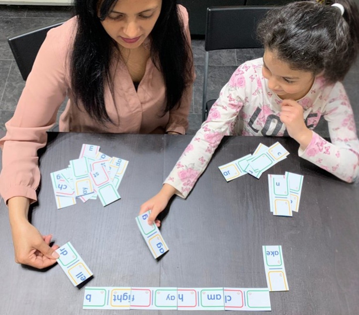 Sabina Bashir working with a child using phonics and word-building learning resources at home
